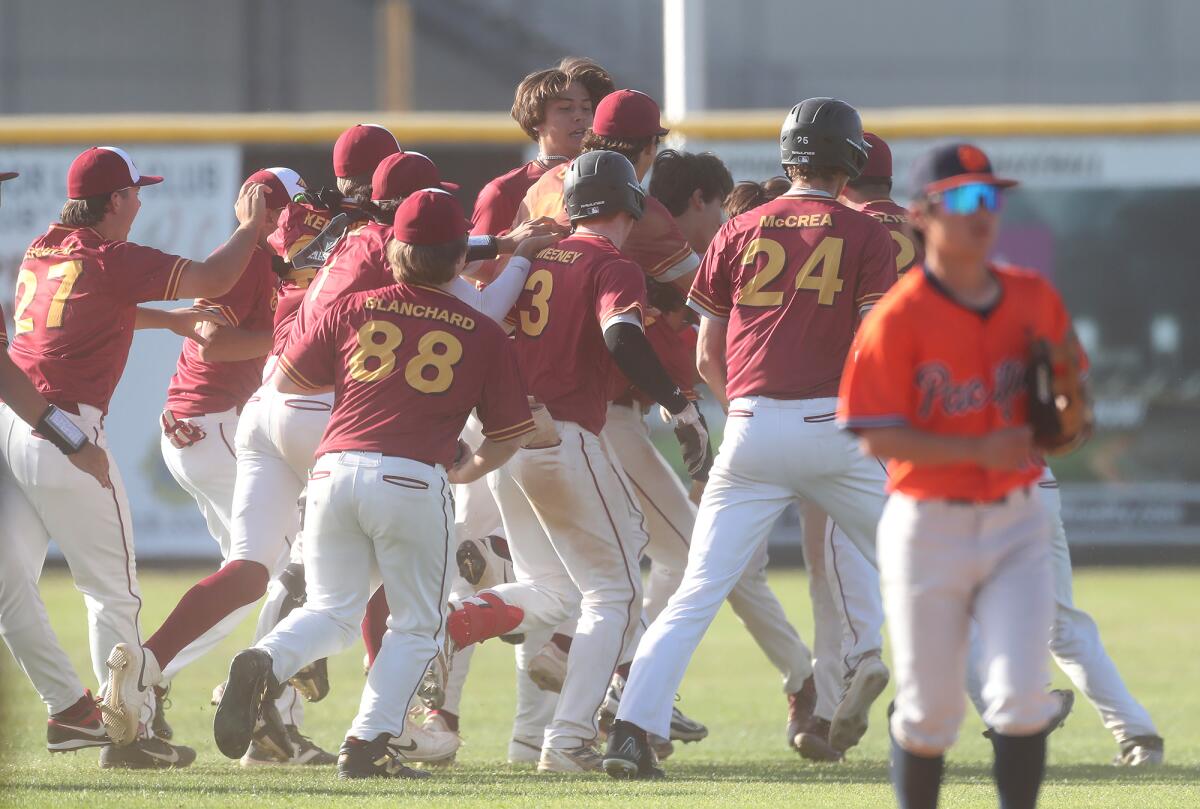 Members of the Estancia High baseball team mob Jake Humphries (4) in the outfield after he hit a walk-off single Friday.