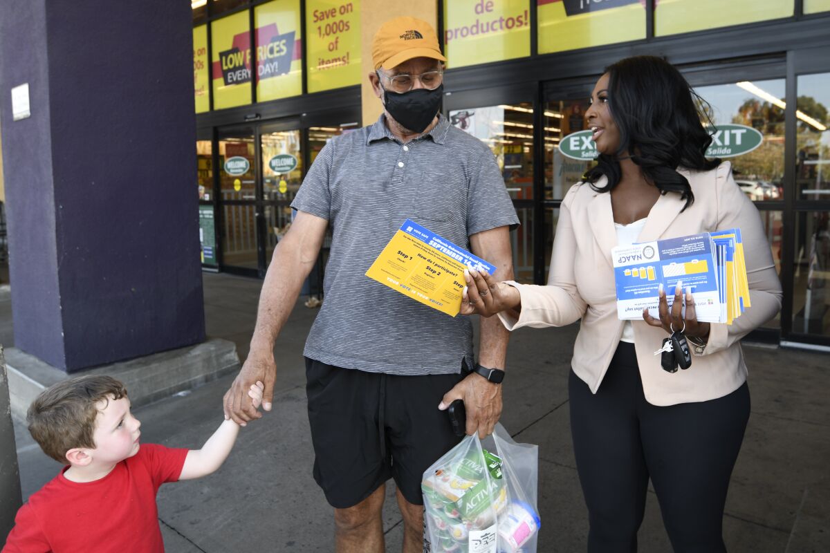 Aeiramique Glass Blake, an NAACP San Diego member, hands out election literature at Jacobs Center in San Diego. 