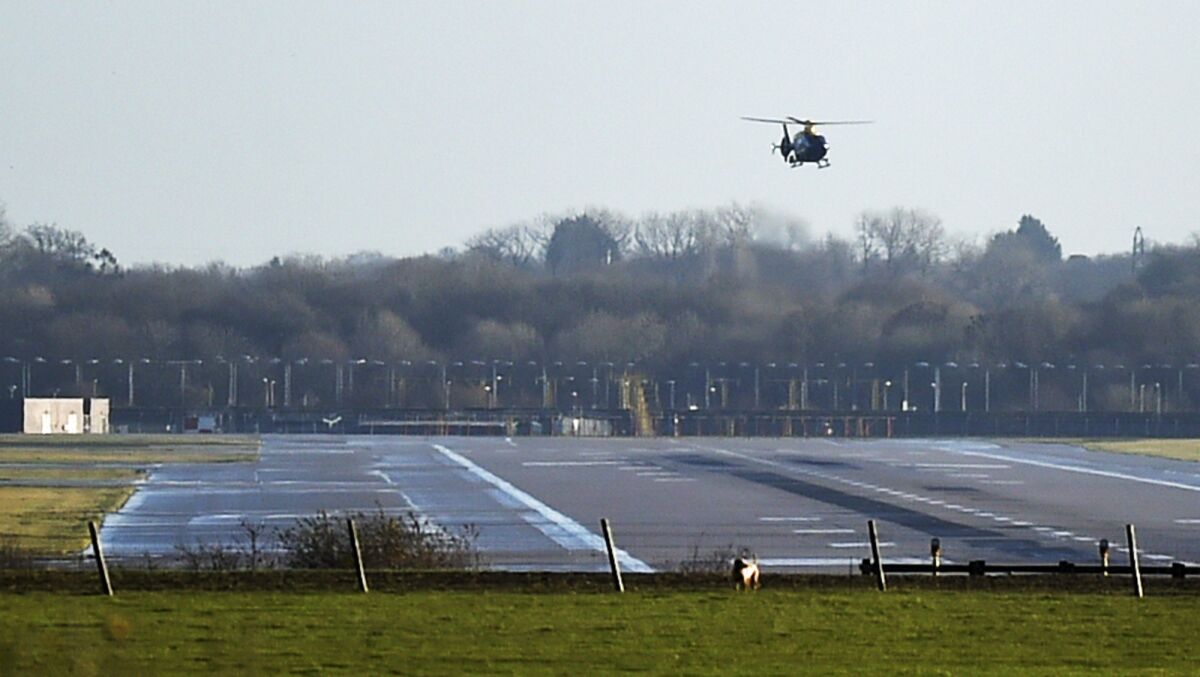 A police helicopter flies over the runway at Gatwick Airport in London. The airport remained closed after drones were spotted over the airfield Wednesday night and Thursday morning.