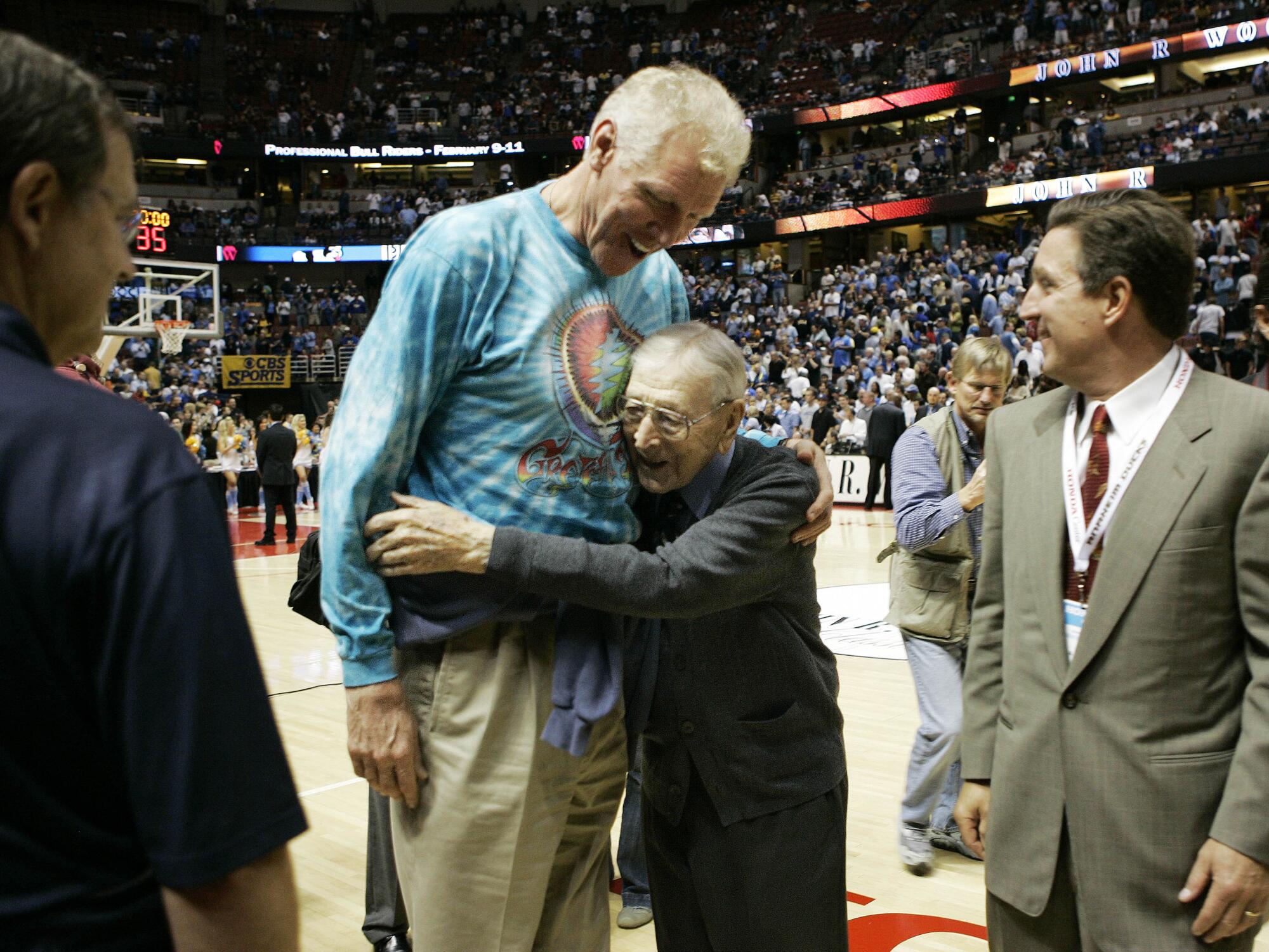 Legendary UCLA basketball coach John R. Wooden, right, hugs his former player Bill Walton.