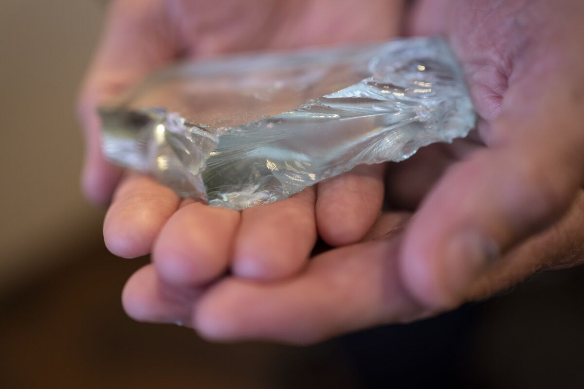 Retired NYPD Officer Ken Winkler, holds a broken piece of glass that he kept from the fallen World Trade Center skyscrapers, which he keeps in his office on Tuesday, Aug. 3, 2021, in New York. "Somebody once asked me, 'How often do you think about it?' I told him it's easier to count the days when you don't think about it," says Winkler, who now manages Manhattan's cruise ship terminal. (AP Photo/Wong Maye-E)