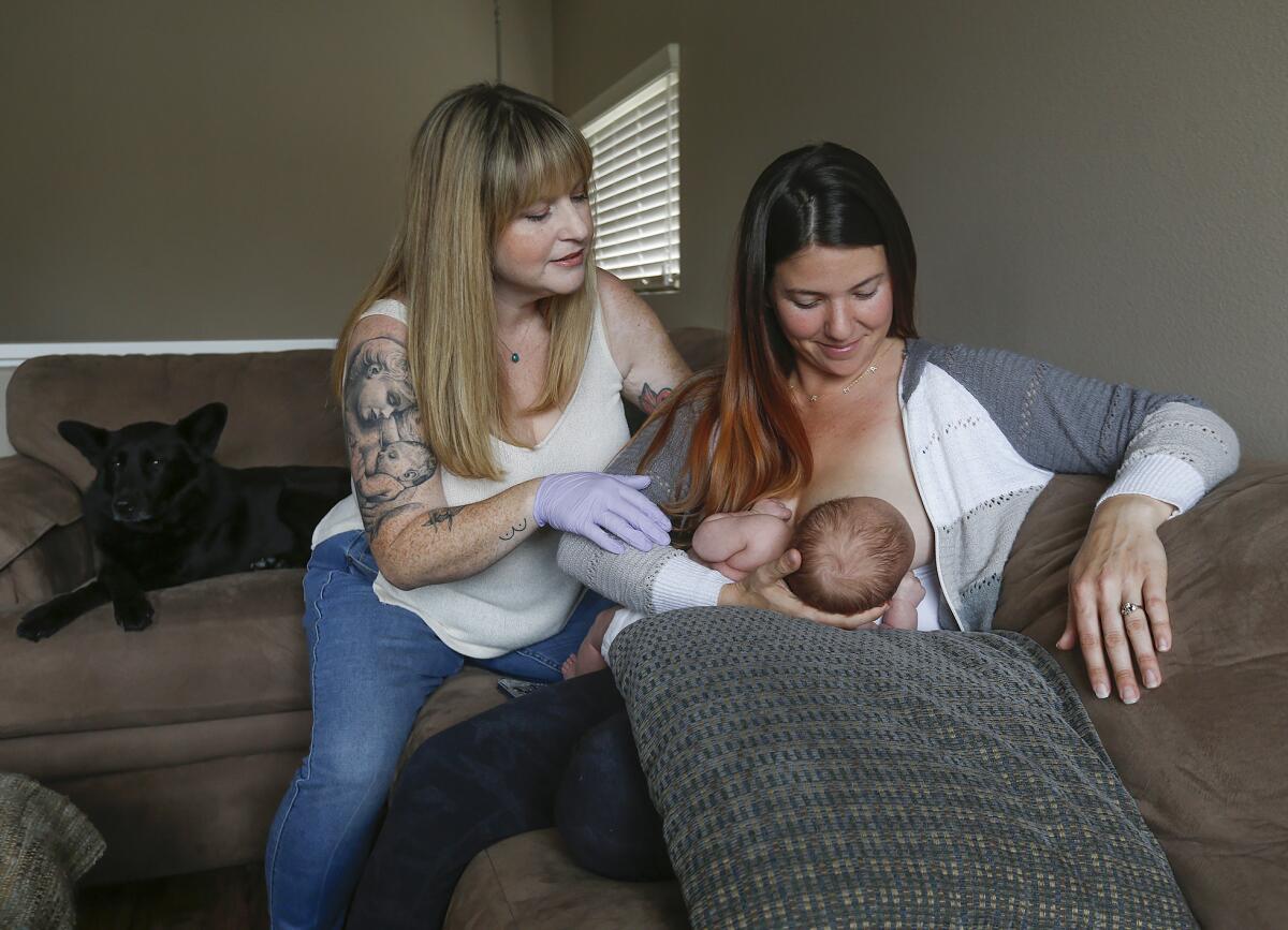 Lactation consultant Rachelle King, left, advises her client Kaitlyn Ramos as she breastfeeds her son Bowen on Thursday.