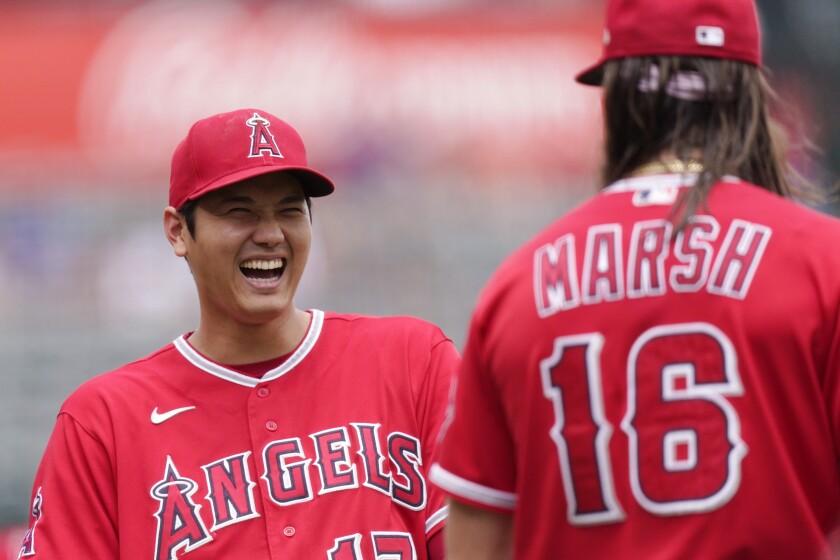Shohei Otani laughs as he talks to Angels outfielder Brandon Marsh ahead of Sunday's loss to the Texas Rangers.