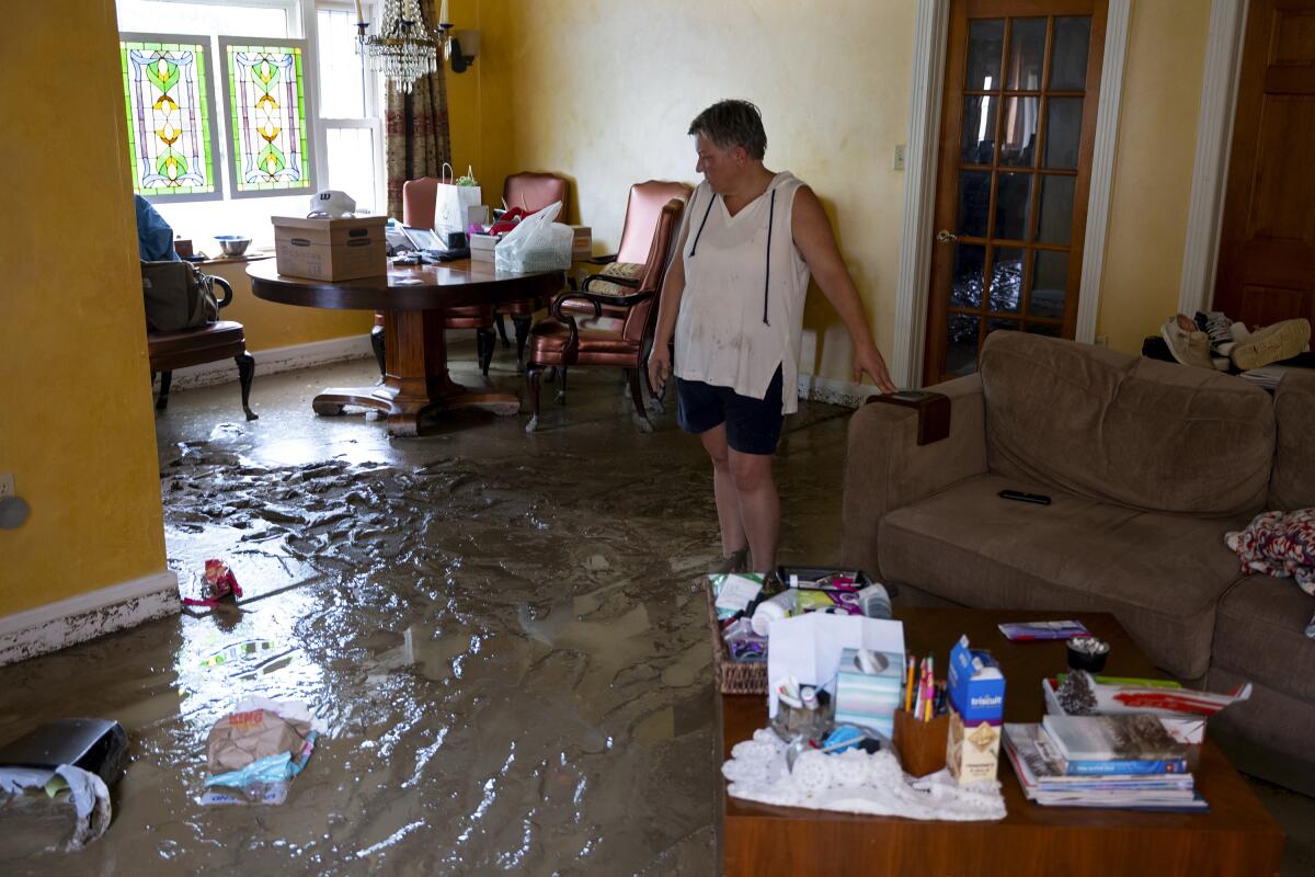 A woman walks in a flood-damaged home.