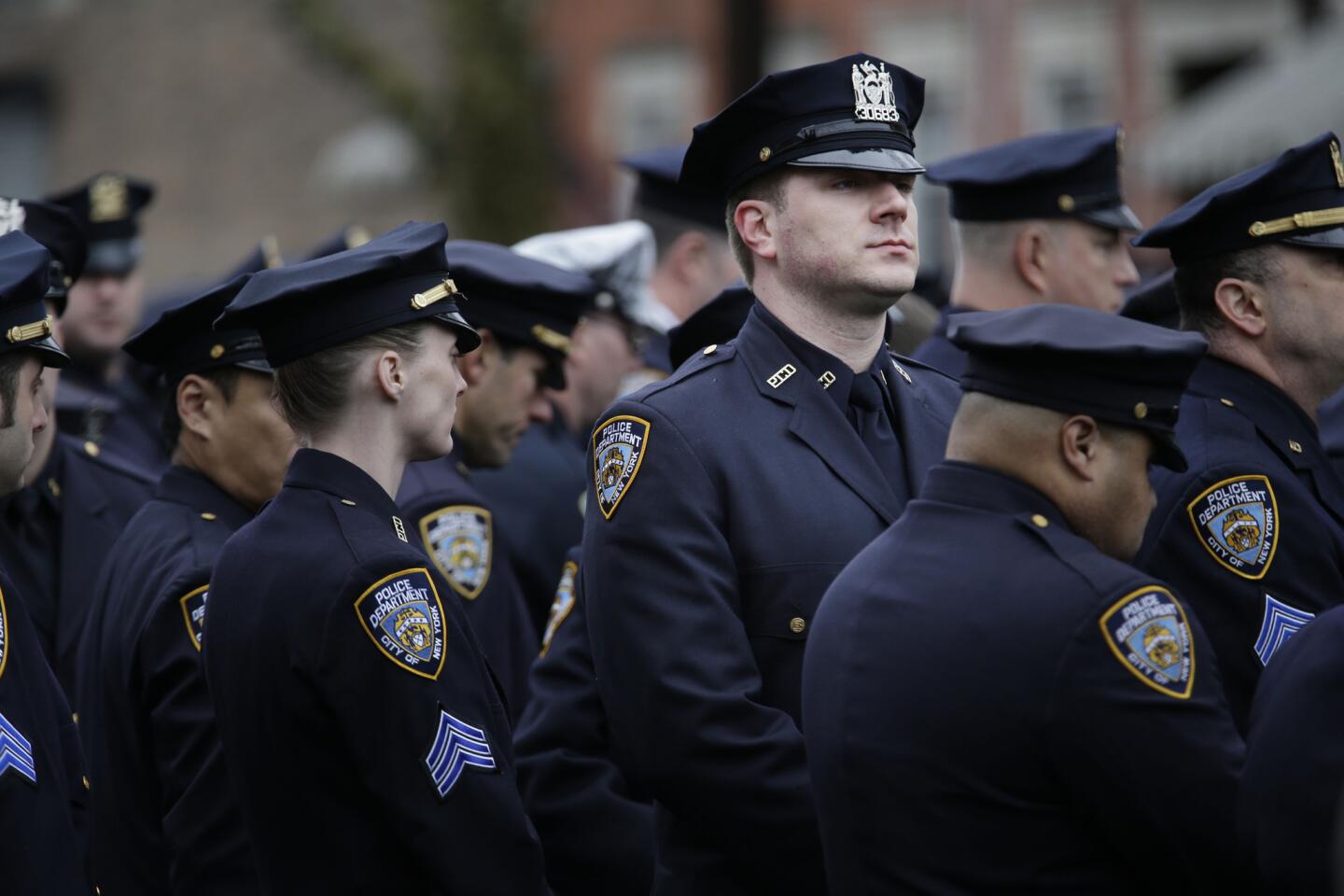 A police officer turns his back to a large screen where New York City Mayor Bill de Blasio speaks during the funeral of Officer Wenjian Liu in New York on Jan. 4.