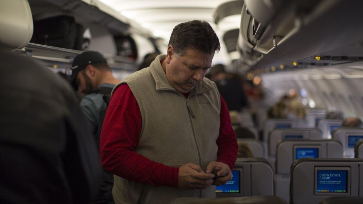 A passenger on Jet Blue Airways checks his cellphone before disembarking at the Long Beach airport. The Department of Transportation has completed accepting public comments on a plan to continue a ban on cellphone calls on planes.