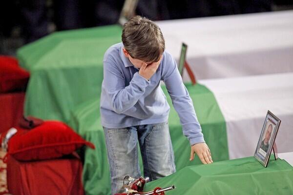 The 7-year-old son of Lt. Antonio Fortunato touches his father's coffin in the Basilica of St. Paul Outside the Walls in Rome. A state funeral was held Monday for six Italian soldiers killed by a suicide car bomber in Kabul, Afghanistan, last Thursday. The service was officiated by the military ordinary for Italy, Msgr Vincenzo Pelvi.
