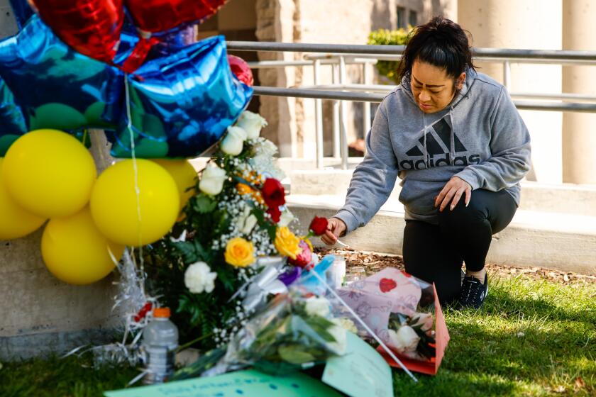 Cudahy, CA - February 13: A community member is lights a candle at a memorial outside of Ellen Ochoa Learning Center where a deadly shooting killed a boy on Tuesday, Feb. 13, 2024 in Cudahy, CA. (Jason Armond / Los Angeles Times)