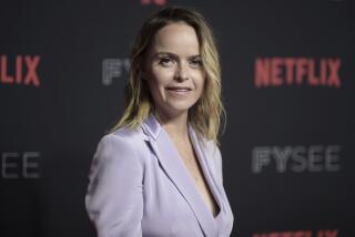 Taryn Manning in a lilac suit jacket posing at an angle at a Netflix red carpet event