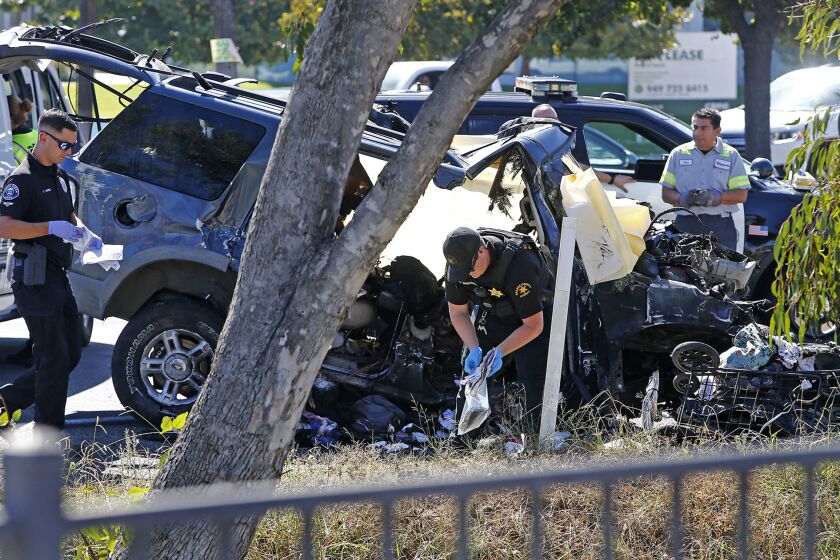 An Orange County Sheriff collects items as the Costa Mesa police investigate a fatal collision that took place early Friday morning near the intersection of Newport Boulevard and17th Street, where a vehicle reportedly crashed into a culvert and became engulfed in flames, trapping the driver inside. (Kevin Chang / Daily Pilot)