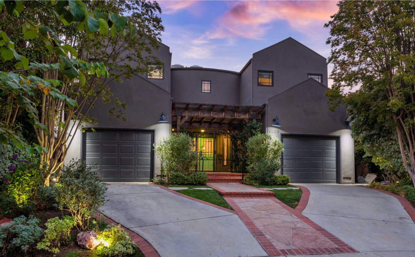 The striking gray home opens to more neutral interiors and a private backyard with a pool under string lights.
