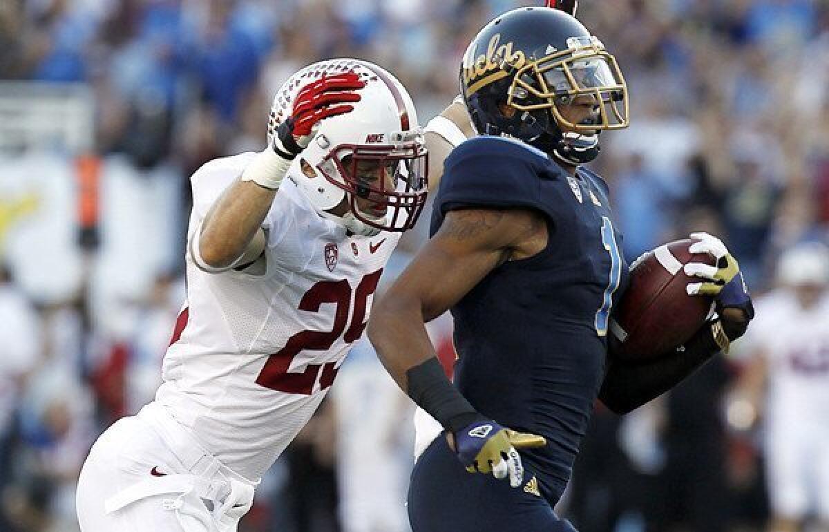 Bruins receiver Shaquelle Evans is chased down by Stanford safety Ed Reynolds after hauling in a pass for a 71-yard gain in the first quarter Saturday at the Rose Bowl.