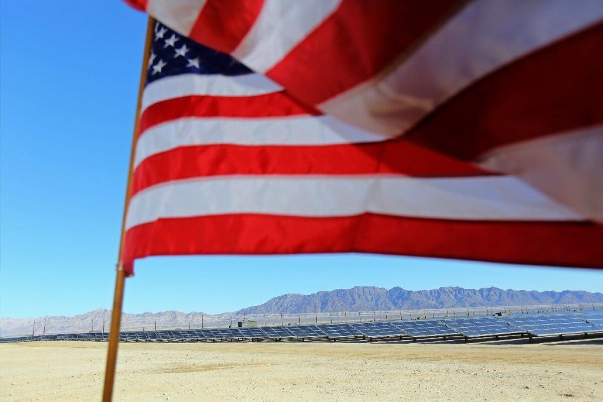 The American flag soars in the wind on Feb. 9, 2015 at the 550-megawatt Desert Sunlight solar farm in eastern Riverside County, which sells electricity to Pacific Gas & Electric and Southern California Edison.
