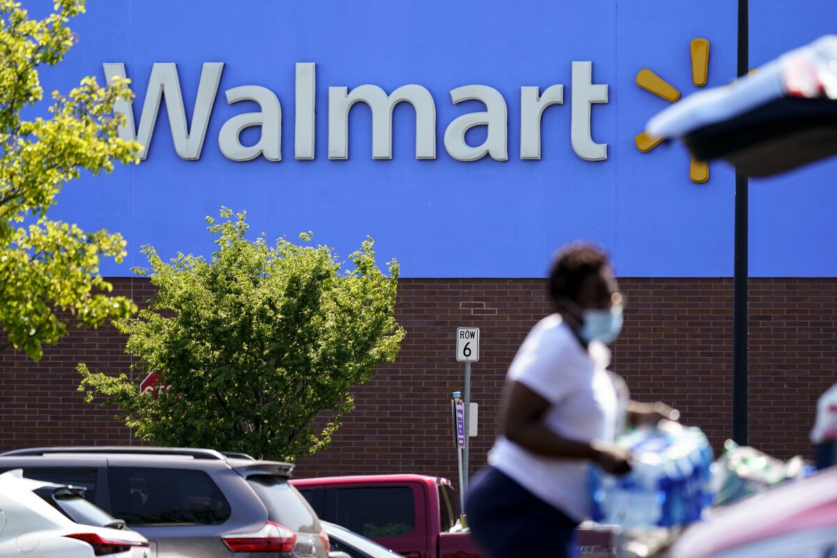 A woman carries bottles of water outside a Walmart.