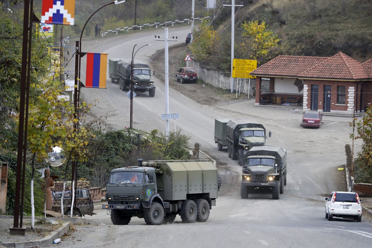 Green military trucks drive through a street in Stepanakert in Nagorno-Karabakh.