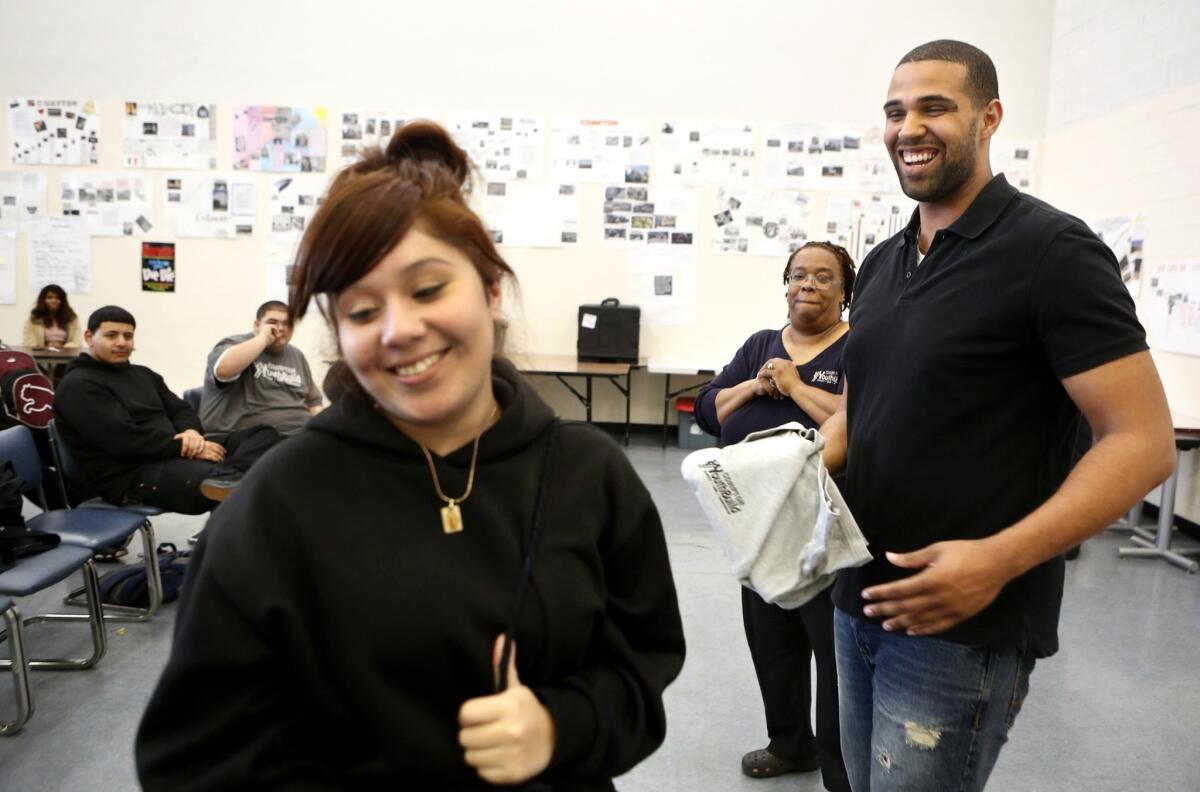 Elizabeth Castillo, 17, left, a student at Compton YouthBuild, reacts after giving Prophet Walker a polo shirt as a gift from the school. Walker, 26, focuses much of his time on people who might be left behind. At the Anti-Recidivism Coalition, where onetime felons can stop by to talk and take classes, he teaches a public speaking course. At Watts United Weekends, he works with inner-city middle-schoolers at Canyon Creek Camp in the mountains near Lake Hughes.