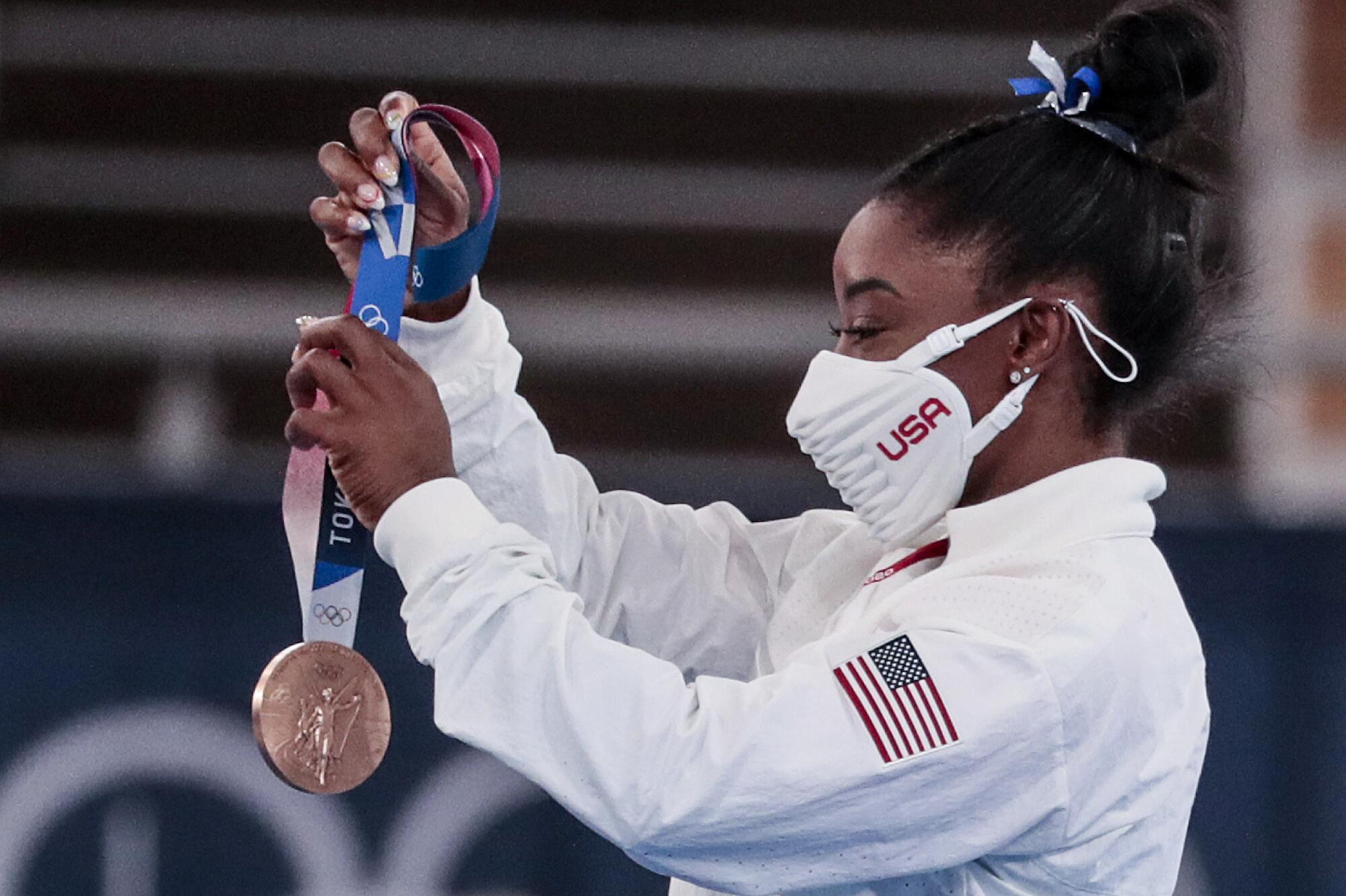 Simone Biles holds the bronze medal she won in the balance beam final.