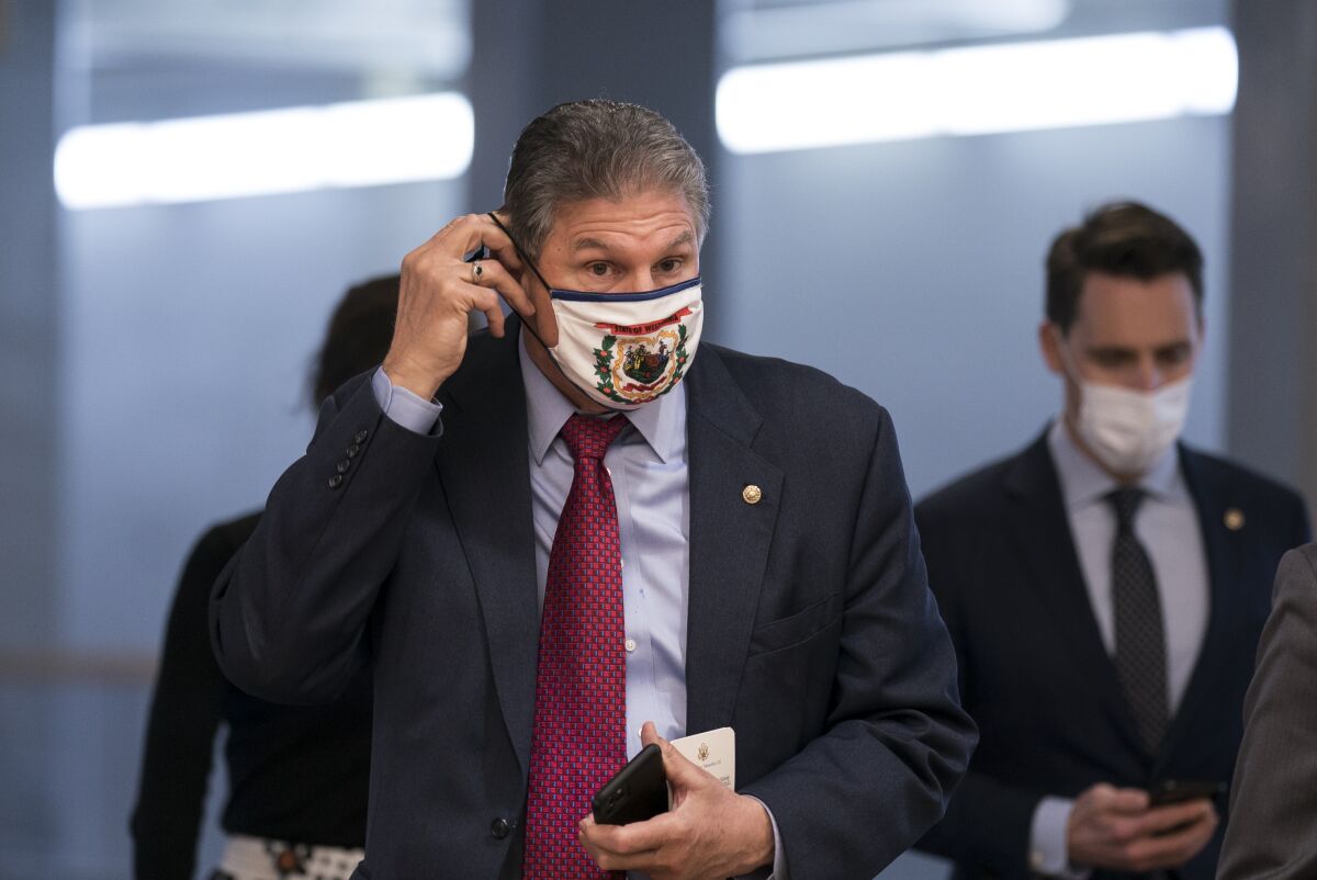 Sen. Joe Manchin (D-W.Va.) adjusts his face mask as he arrives for votes at the Capitol on Tuesday.