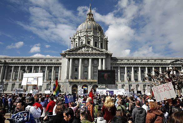 People gather to watch a large television screen at City Hall in San Francisco.