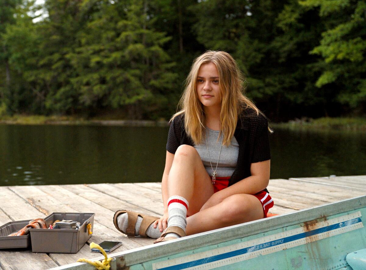 A young woman sits looking thoughtful on a boat dock.