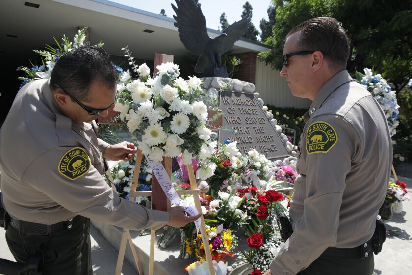 El Monte, CA - June 15: Lt. Manuel Arana, left, and Capt. Jim Teeples, from South Gate police place flowers at a memorial for two dead El Monte police officers at El Monte Police Department at Civic Center on Wednesday, June 15, 2022 in El Monte, CA. (Irfan Khan / Los Angeles Times)