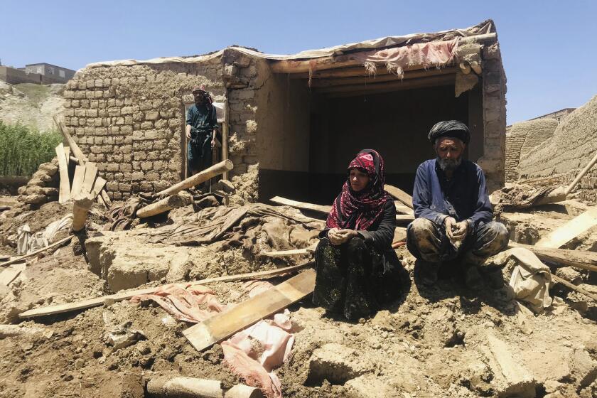 An Afghan couple sit near their damaged home after heavy flooding in Ghor province in western Afghanistan, Saturday, May 18, 2024. Flash floods from heavy seasonal rains in Ghor province dozens of people and dozens remain missing, a Taliban official said on Saturday, adding the death toll was based on preliminary reports and might rise. (AP Photo/Omid Haqjoo)