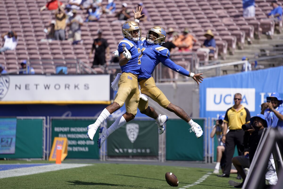 UCLA quarterback Dorian Thompson-Robinson and receiver Titus Mokiao-Atimalala celebrate in the end zone.