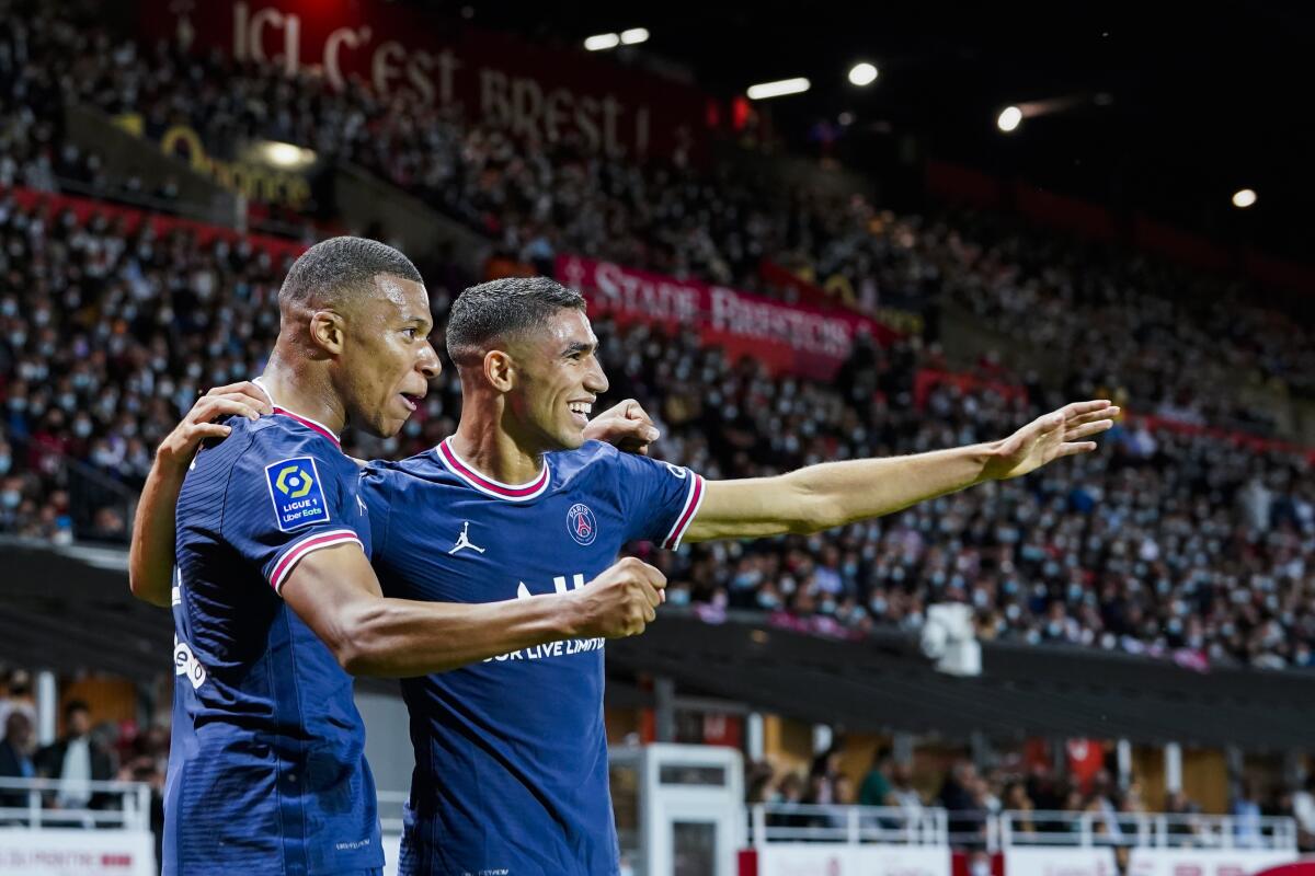 FILE - PSG's Kylian Mbappe, left, celebrates with teammate PSG's Achraf Hakimi after scoring his side's second goal during a French League One soccer match between Brest and PSG at the Francis-Le Ble stadium in Brest, France, Friday, Aug. 20, 2021. (AP Photo/Daniel Cole, File)