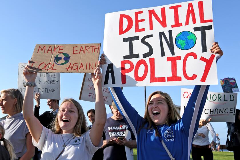 Jordan Pritzl of Aliso Viejo, left, and Merina Addonigio, both from Suka University, hold protest signs during the Climate Strike climate change protest, at Main Beach Park in Laguna Beach on Friday, Sept. 20, 2019. People throughout the world came out today to protest against climate change.