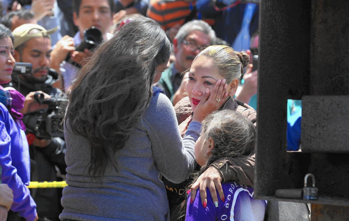 Isela Michel Zavala wipes a tear from her mother, Yudridia Guadalupe Zavala, whose arm is draped over Isela's daughter Briana Montes, as they meet at the Door of Hope at Border Field State Park.