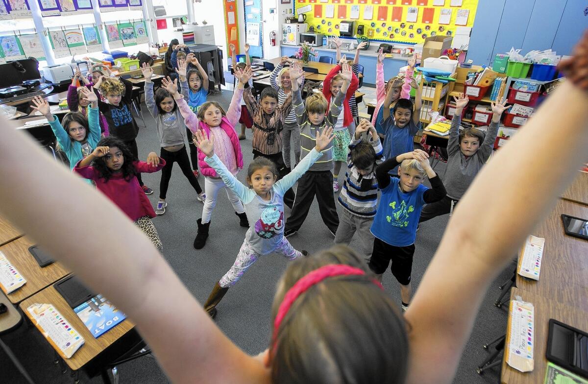 Students in Sabrina Ericastilla's first-grade class at Harbor View Elementary School in Newport Beach follow Stacey Fetterman's yoga instruction on Tuesday. The poses were inspired by the picture book “Nothando’s Journey.”
