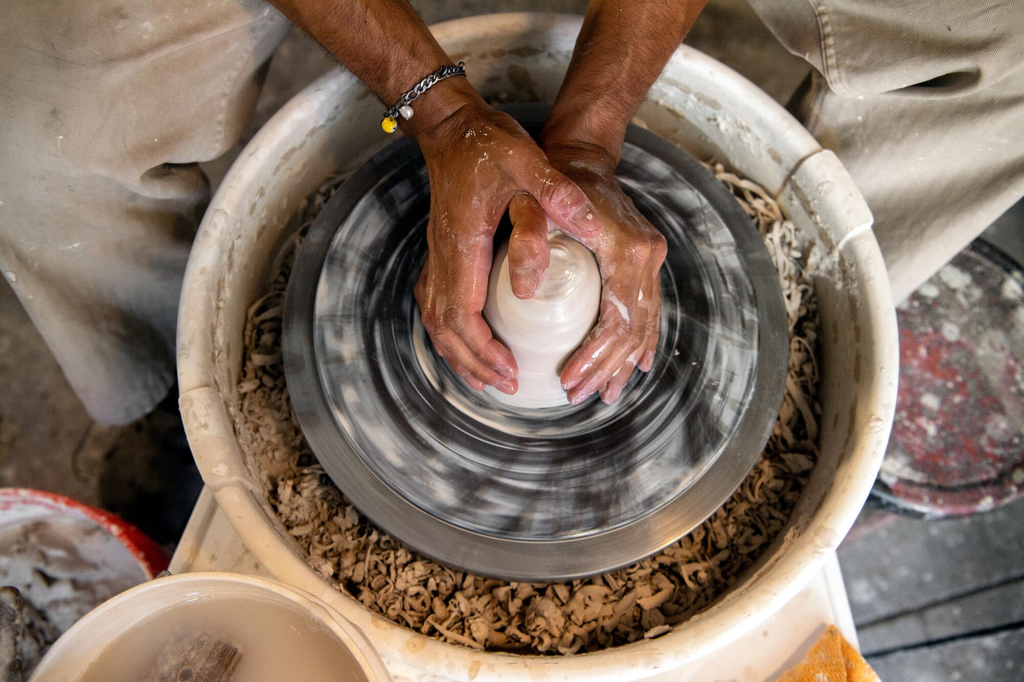 Hands on a pottery wheel shaping a ceramic piece