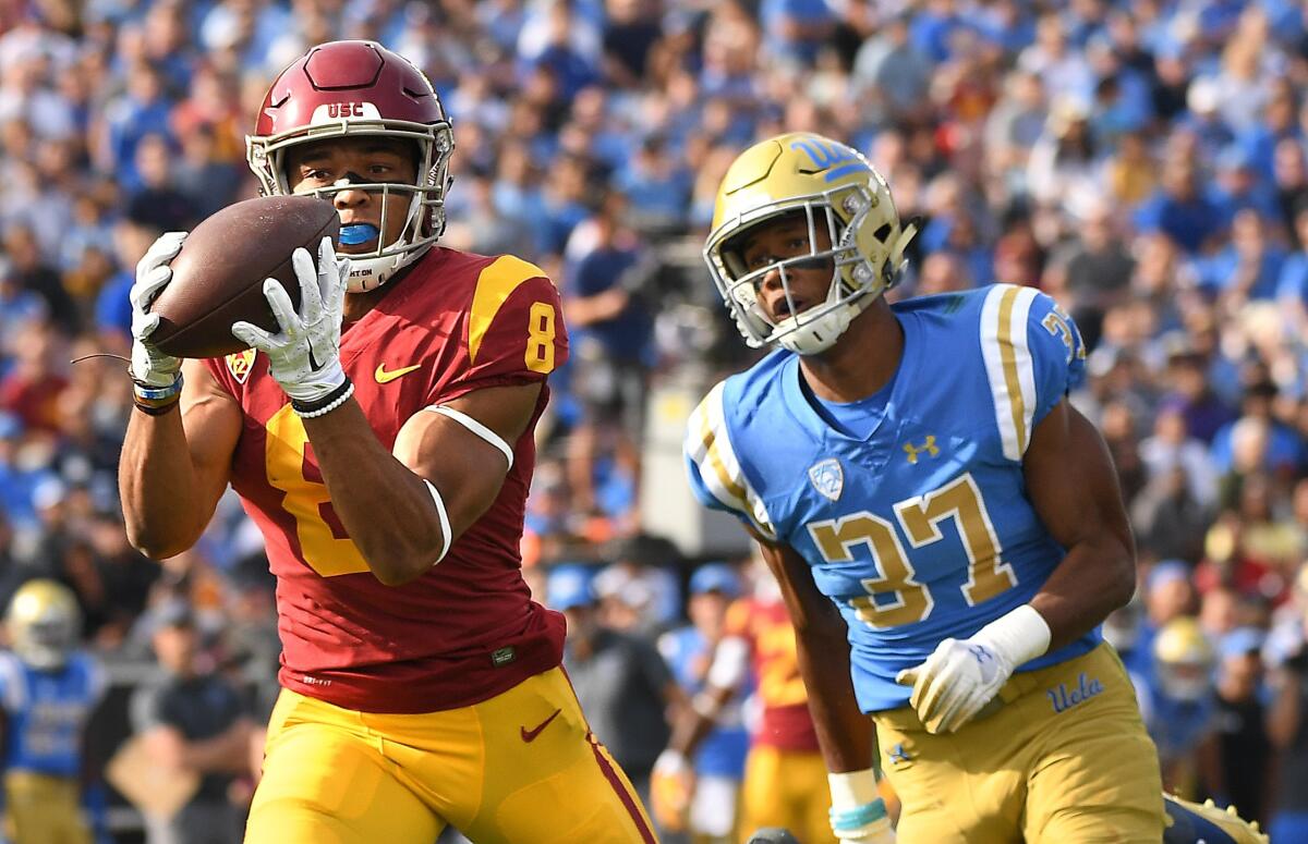 USC wide receiver Amon-ra St. Brown makes a catch in front of UCLA’s Quentin Lake.