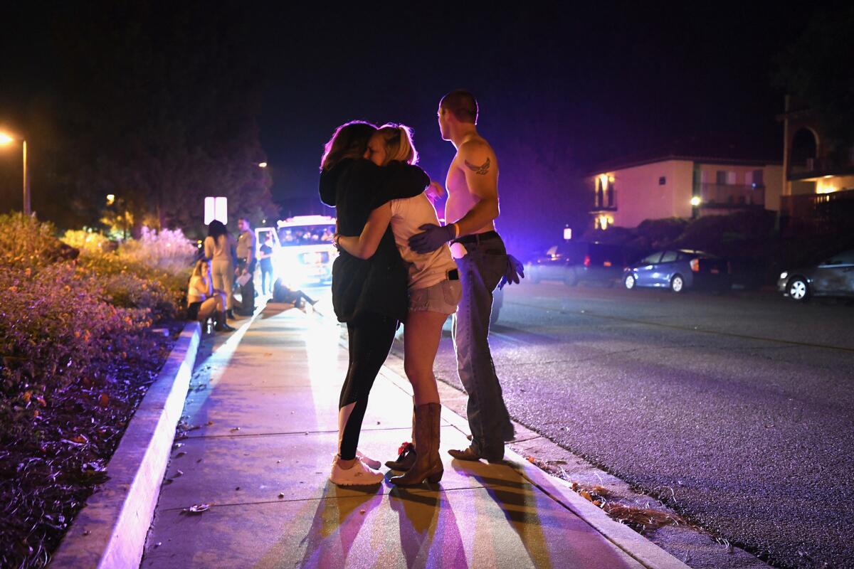 People hug on the side of the road near the Borderline Bar & Grill in Thousand Oaks after multiple people were wounded Wednesday night.
