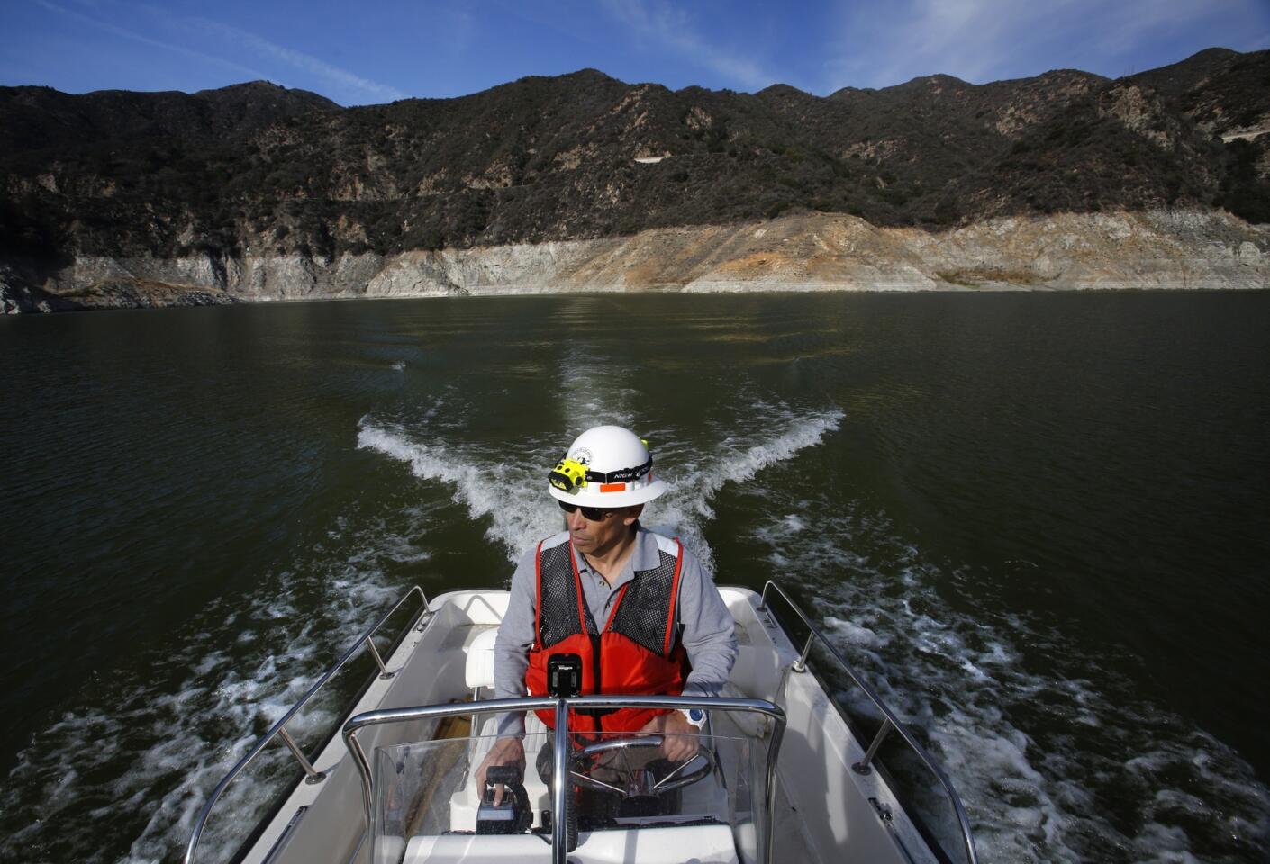 San Gabriel Dam operator Herbert Romero pilots an inspection boat through the San Gabriel Reservoir near Azuza. The more than 121-foot-high "bathtub ring" around the reservoir's edge reveals how far the water level has dropped from when it was full in 2005.