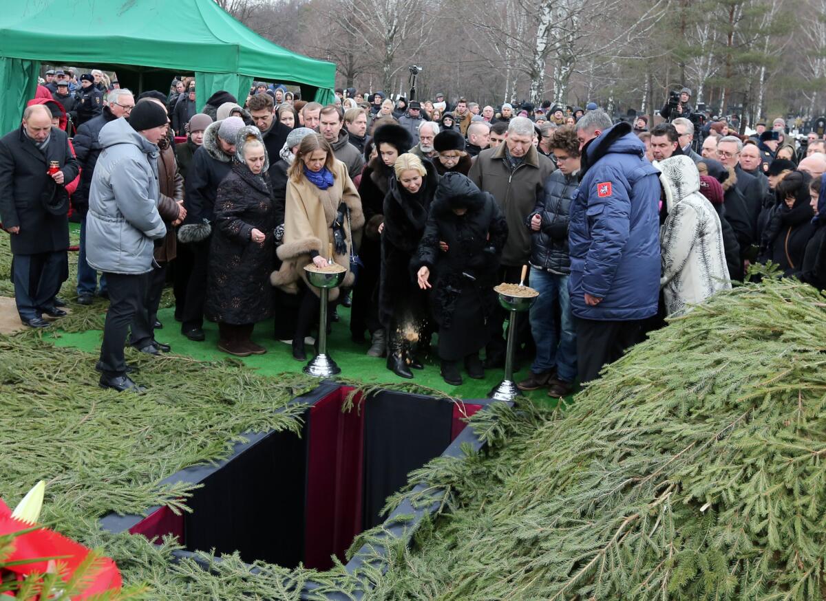 Boris Nemtsov's mother, Dina Eidman, center, leans forward to symbolically throws a handful of earth into her son's grave on Tuesday at his burial in Moscow.