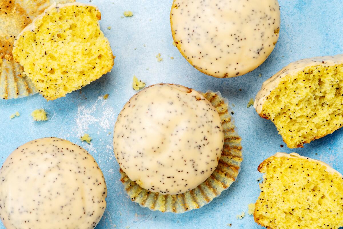 Passionfruit and Poppy Seed Muffins, whole and halved, in paper wrappers.