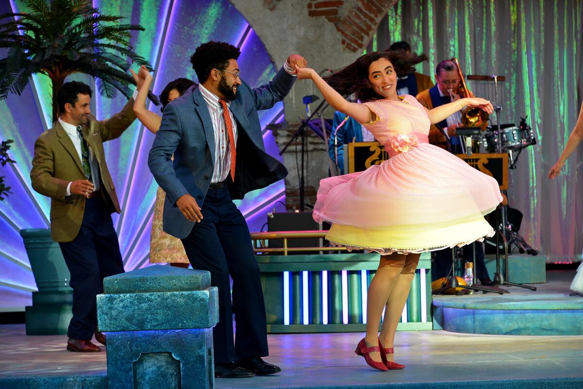 Four people are dancing on stage. A man is twirling a woman in front.
