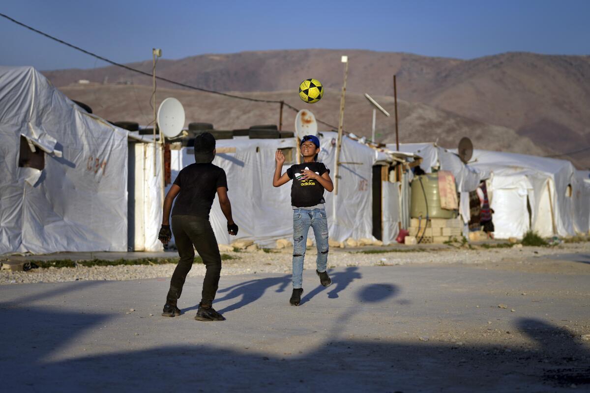 FILE - Syrian children play soccer near their tented homes at a refugee camp in the town of Bar Elias, in the Bekaa Valley, Lebanon, July 7, 2022. A Syrian Cabinet minister said Monday, Aug. 15, 2022, that Syrian refugees in neighboring Lebanon can start returning home, where he said they will get all the help they need from authorities. Tiny Lebanon is home to 1 million Syrian refugees who fled war in their country after the conflict began in March 2011. (AP Photo/Bilal Hussein, File)