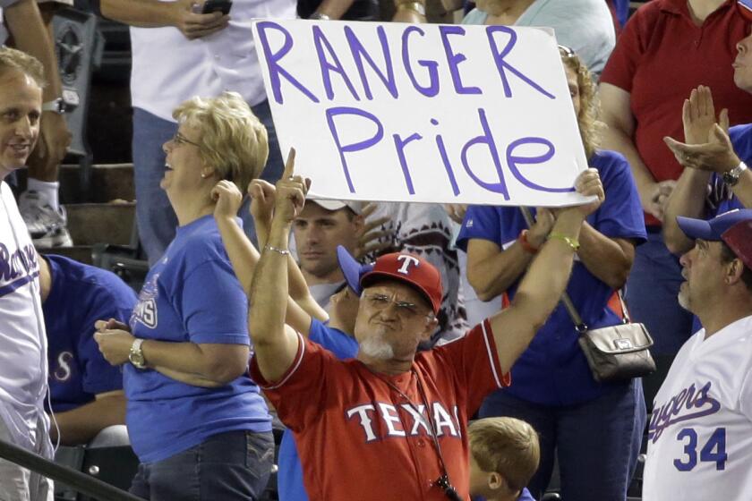 A Texas Rangers fan holds up a sign that reads "Rangers Pride" in the seventh inning of a baseball game