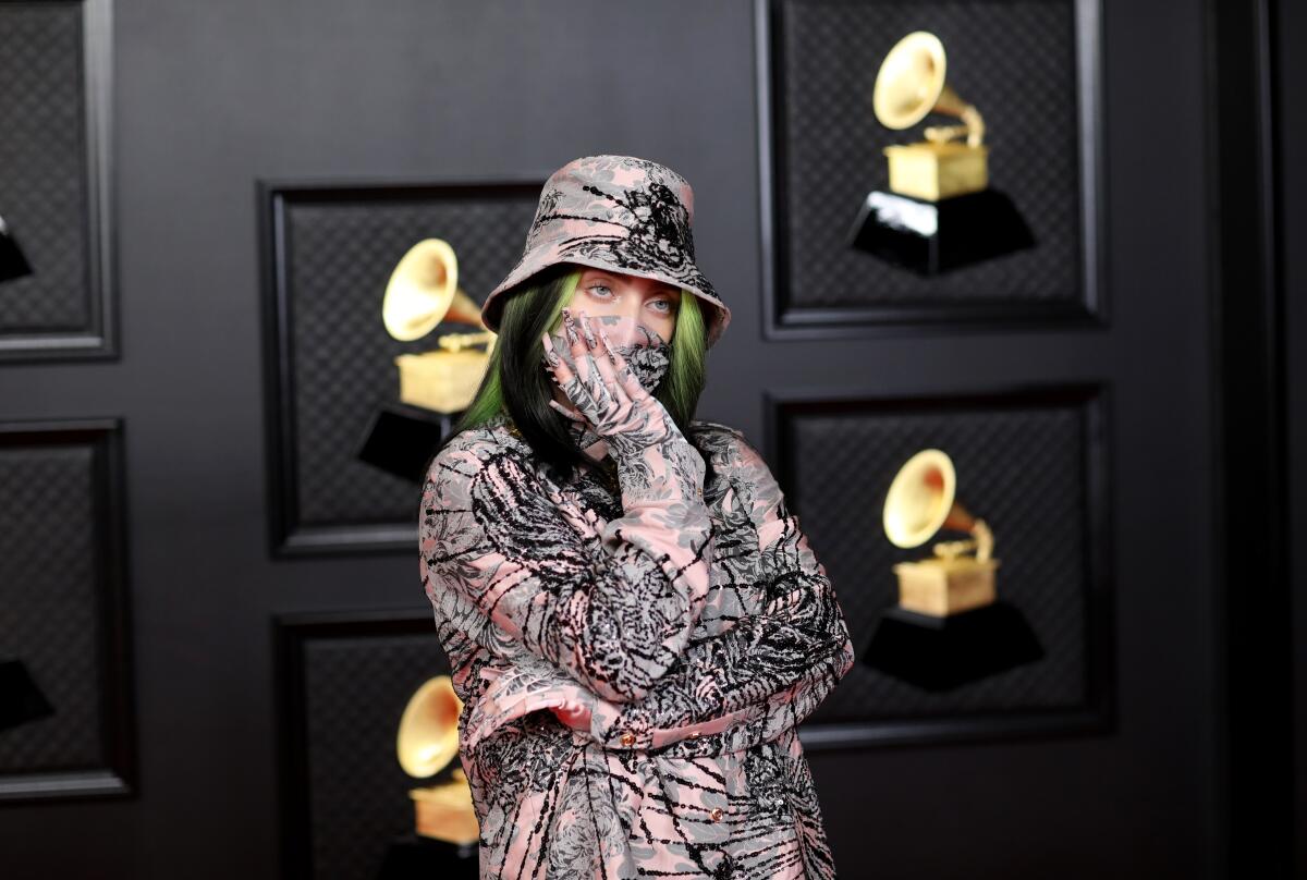 Billie Eilish posing with her arms crossed and hand over her mouth at the Grammy Awards.