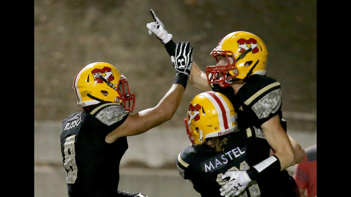 Mission Viejo wide receiver Zack Taylor, right, is congratulated by teammates after scoring a touchdown on a long catch and run against Norco in a game earlier in the season.