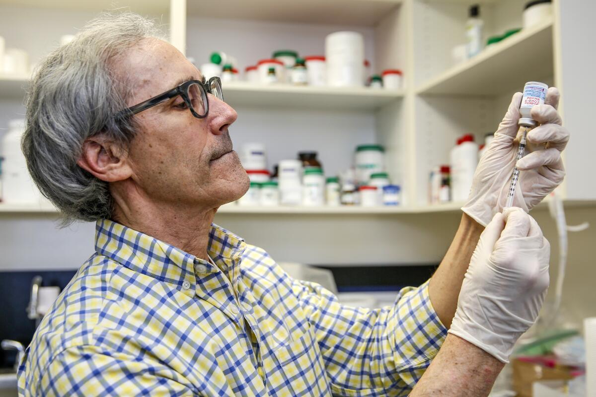 A man in glasses prepares a syringe