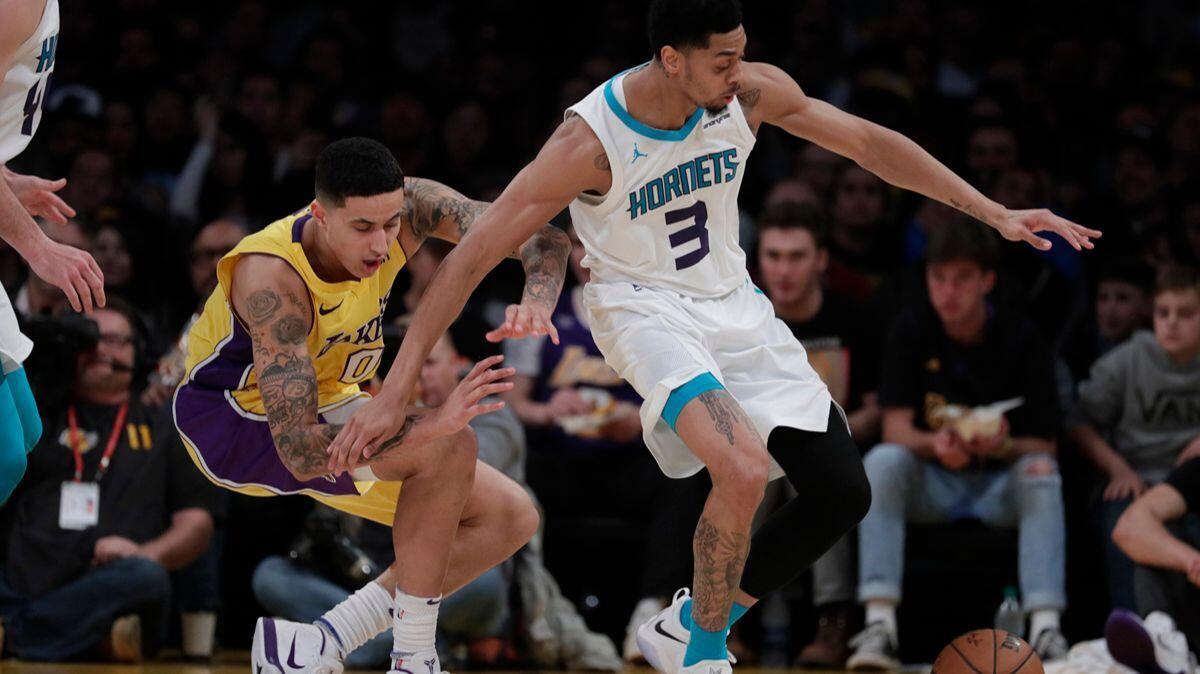 Lakers forward Kyle Kuzma, left, stumbles away possession of the ball as Charlotte Hornets guard Jeremy Lamb goes after it during second-half action at Staples Center on Friday.