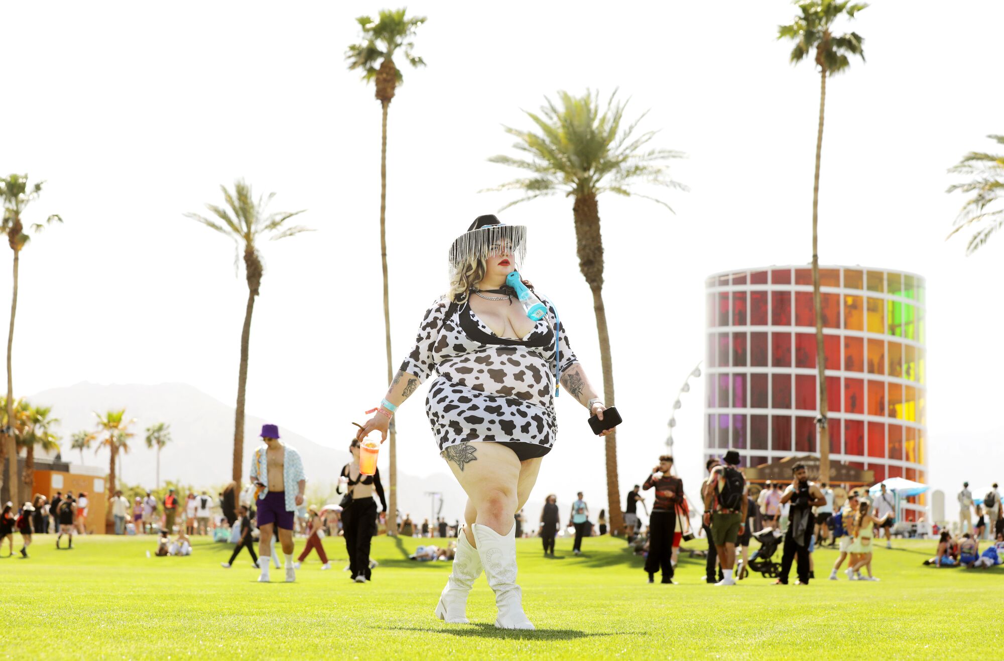 A woman walks on grass at Coachella with palm trees behind her