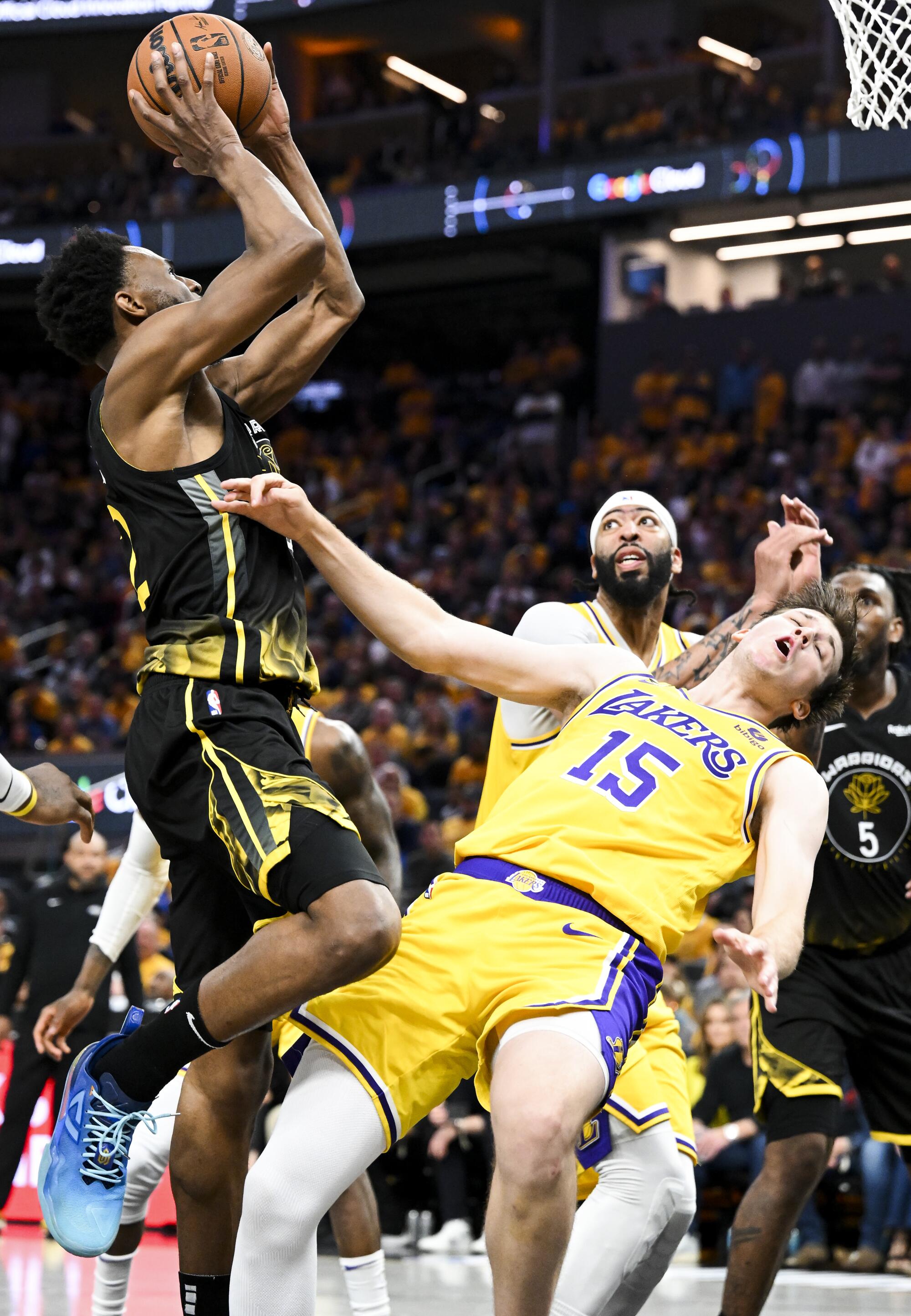 Lakers guard Austin Reaves, right draws a charge on a drive by Warriors forward Andrew Wiggins.