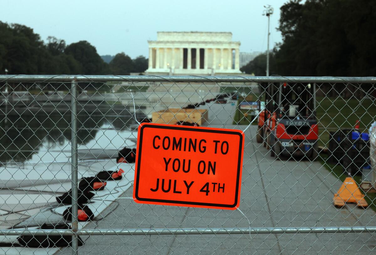 A sign on a chain-link fence says "Coming to you on July 4th."