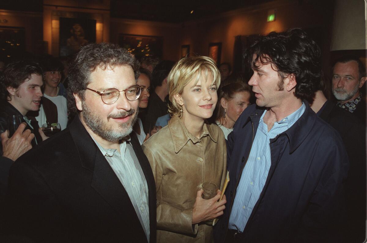 A blond woman stands between two men at a party