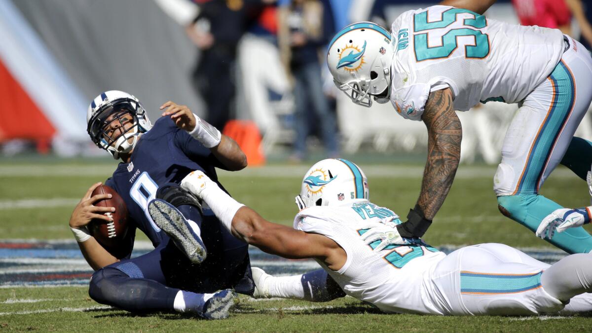 Titans quarterback Marcus Mariota (8) is sacked by Dolphins defensive end Olivier Vernon (50) in the first half Sunday.
