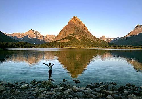A young woman greets the dawn as it lights up mountains beyond Swiftcurrent Lake. Patches of white only hint at the region's history: More than 20,000 years ago, an ice sheet covered this part of northwestern Montana so deeply that only the tallest mountains were visible. The pressure of the ice carved the horns, arêtes, cirques and hanging valleys for which Glacier is known. Toward the end of the 19th century, explorers documented more than 100 ice fields in the Glacier area, some covering nearly 1,000 acres. Today there are 27, and by 2030, scientists predict, all of the glaciers will be gone.